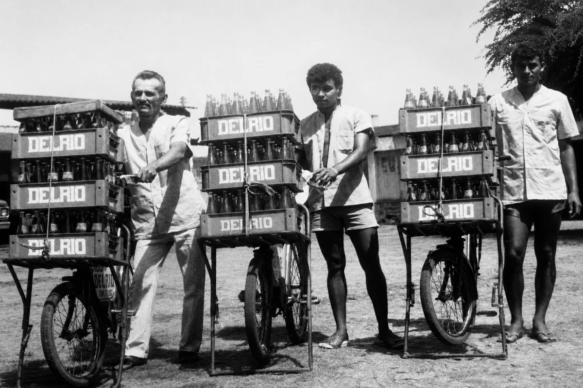 Entregadores da Delrio com bicicletas carregadas de caixas de bebidas.